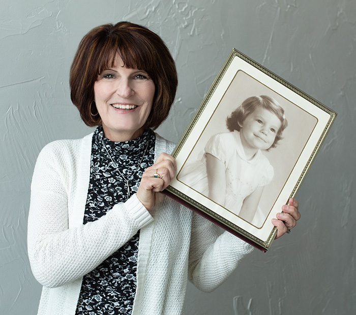 Linda Claussen holding her photo as a young child